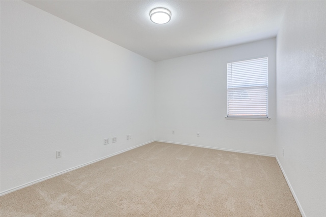 unfurnished room with baseboards and light colored carpet