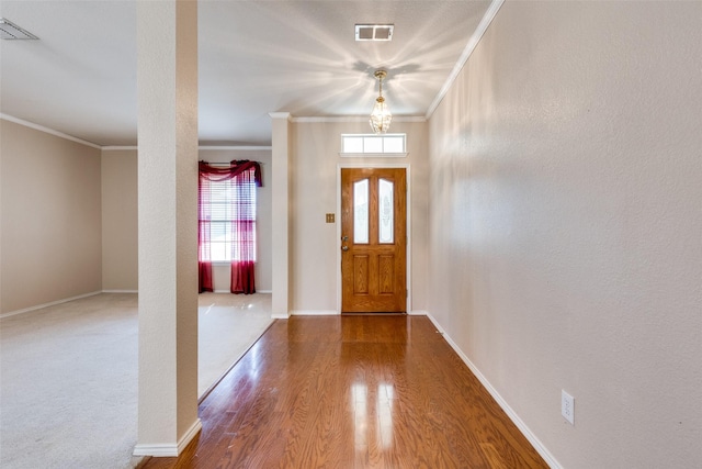 foyer entrance featuring baseboards, wood finished floors, visible vents, and crown molding