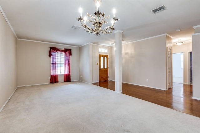 carpeted spare room featuring baseboards, decorative columns, visible vents, and crown molding