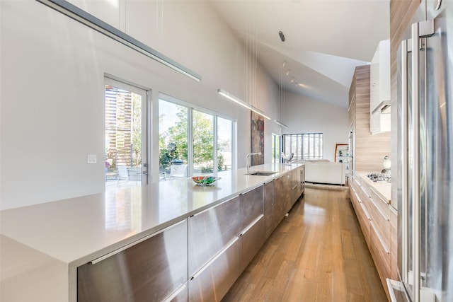 kitchen with sink, white cabinets, lofted ceiling, and light hardwood / wood-style floors