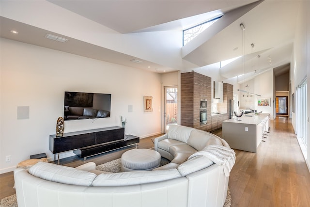 living room featuring light hardwood / wood-style floors and high vaulted ceiling