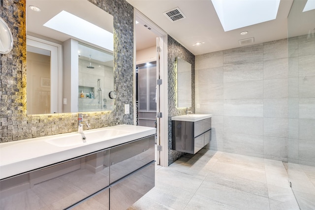 bathroom with a skylight, a shower, tile walls, tile patterned floors, and vanity