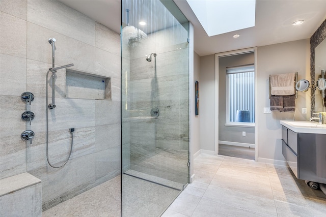 bathroom featuring a skylight, tile patterned floors, vanity, and a tile shower