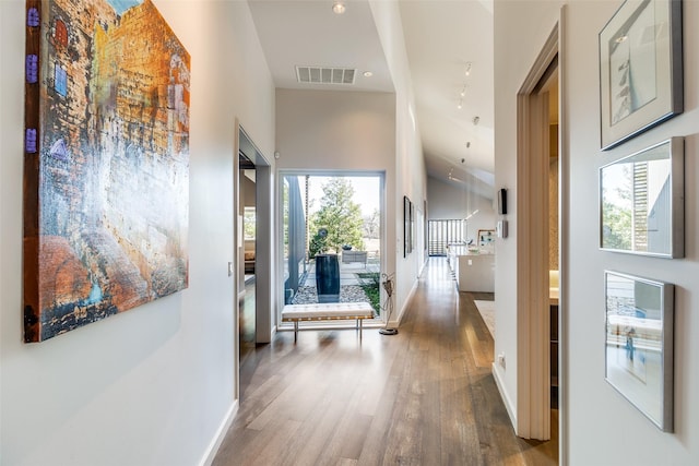 corridor featuring hardwood / wood-style flooring and a towering ceiling