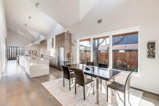 dining room with a high ceiling and light hardwood / wood-style floors