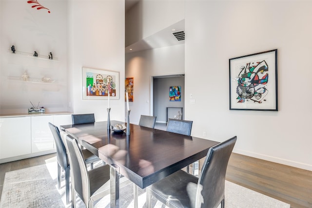 dining room with light hardwood / wood-style flooring and a towering ceiling