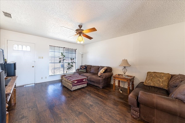 living room with ceiling fan, dark wood-type flooring, and a textured ceiling