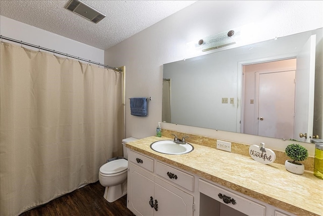 bathroom featuring a textured ceiling, toilet, hardwood / wood-style flooring, and vanity