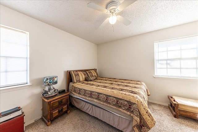 carpeted bedroom with ceiling fan, multiple windows, and a textured ceiling