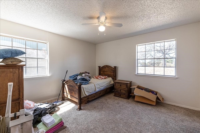 carpeted bedroom featuring ceiling fan, multiple windows, and a textured ceiling