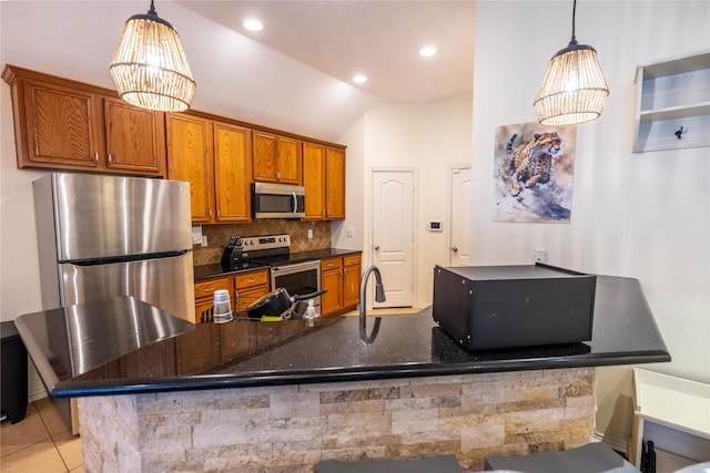 kitchen with light tile patterned flooring, appliances with stainless steel finishes, pendant lighting, and tasteful backsplash