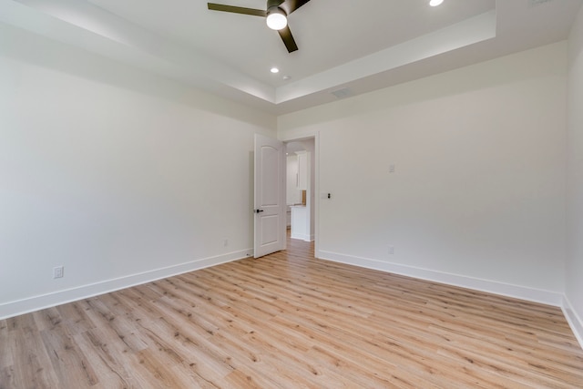 spare room featuring ceiling fan, a tray ceiling, and light wood-type flooring