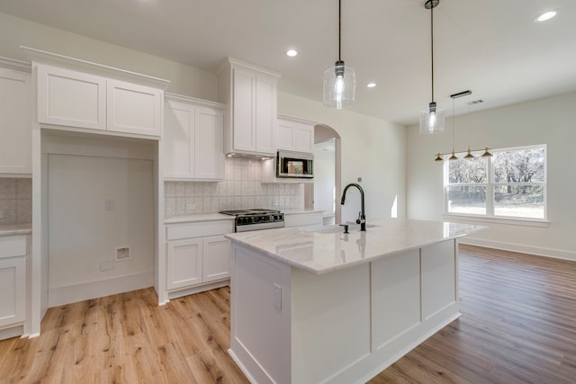 kitchen with white cabinets, stainless steel appliances, an island with sink, sink, and hanging light fixtures