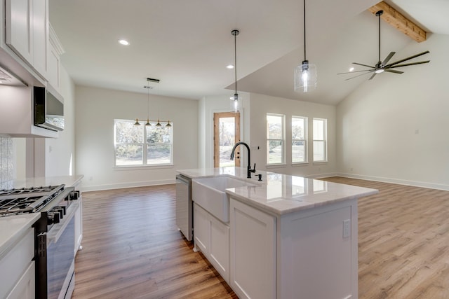 kitchen featuring white cabinets, stainless steel appliances, an island with sink, sink, and hanging light fixtures