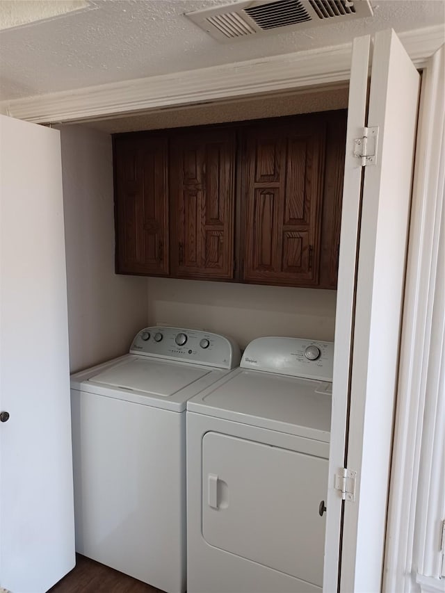 washroom with cabinets, separate washer and dryer, and dark wood-type flooring