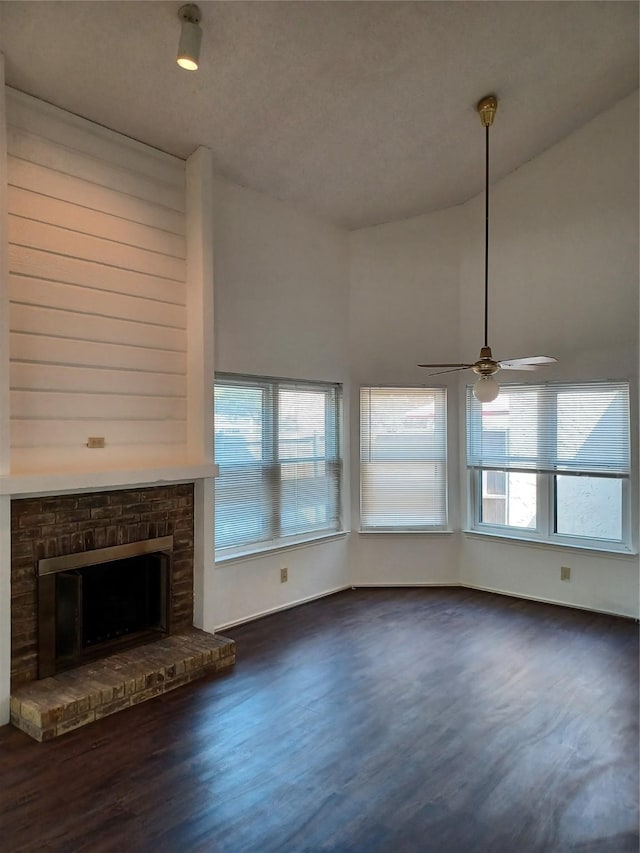 unfurnished living room featuring ceiling fan, a fireplace, dark hardwood / wood-style flooring, and lofted ceiling