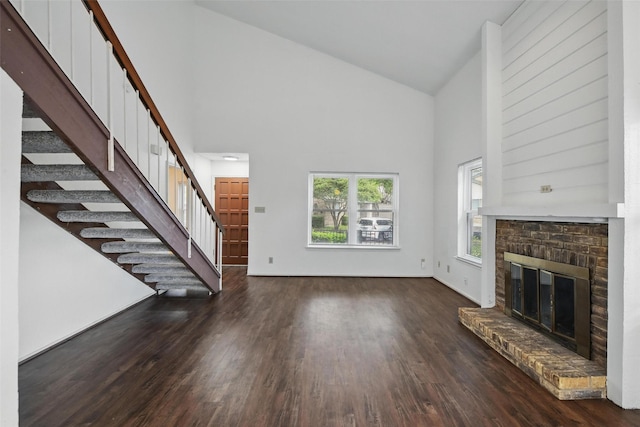 821 Dublin Dr Unit 203, Richardson, TX 75080 - unfurnished living room featuring a brick fireplace, high vaulted ceiling, stairway, and wood finished floors