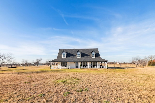 view of front of property featuring covered porch, a front yard, and a rural view