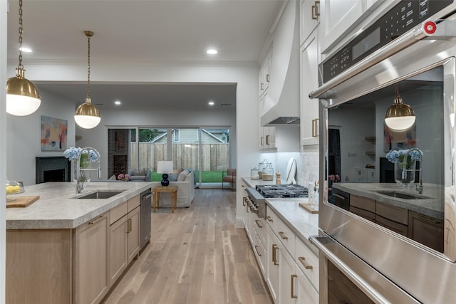 kitchen featuring tasteful backsplash, sink, hanging light fixtures, light wood-type flooring, and appliances with stainless steel finishes