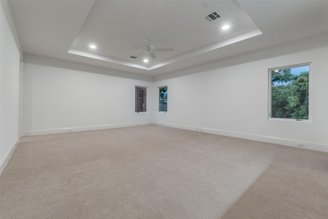 spare room with light carpet, ceiling fan, and a tray ceiling