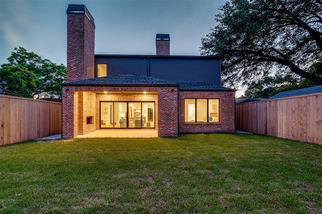 back house at dusk with a lawn