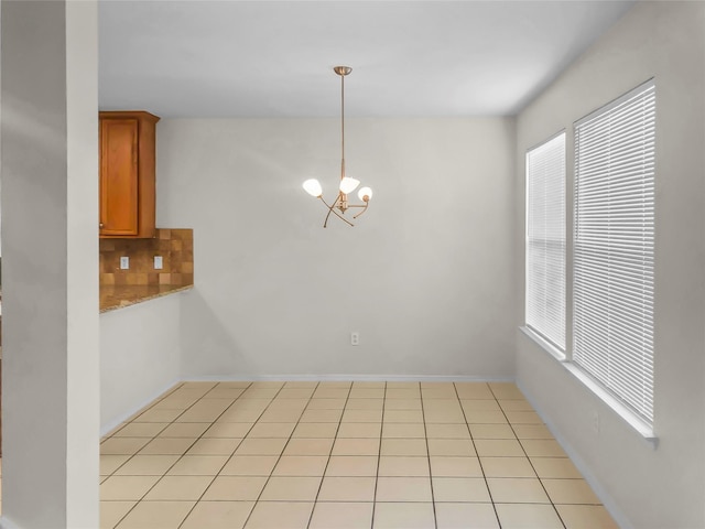 unfurnished dining area featuring light tile patterned floors and a notable chandelier