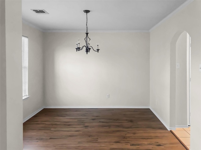 empty room featuring plenty of natural light, dark hardwood / wood-style flooring, ornamental molding, and an inviting chandelier