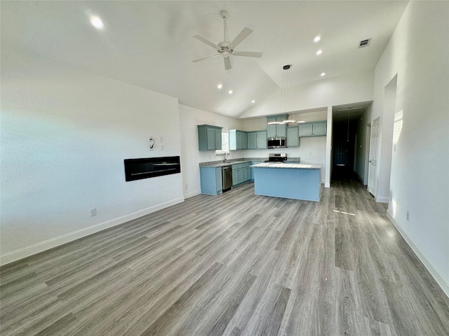 kitchen featuring ceiling fan, a center island, hanging light fixtures, appliances with stainless steel finishes, and high vaulted ceiling