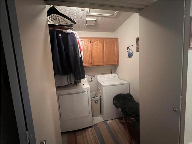 laundry room featuring washing machine and dryer, a textured ceiling, and cabinets