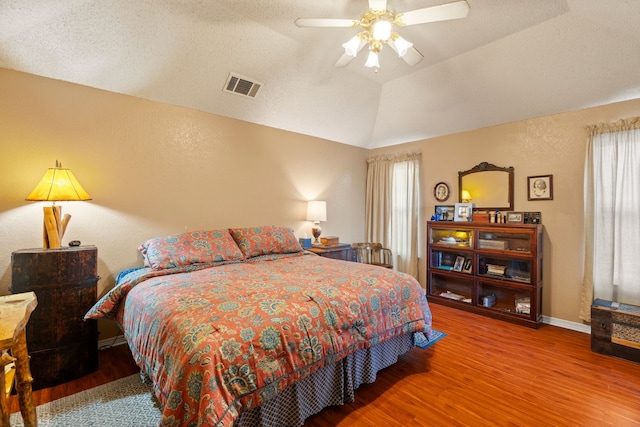 bedroom featuring ceiling fan, hardwood / wood-style floors, vaulted ceiling, and a raised ceiling