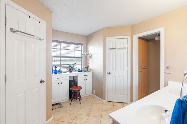 bathroom with a textured ceiling, vanity, and tile patterned flooring