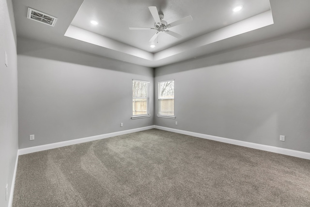 empty room with ceiling fan, carpet, and a tray ceiling