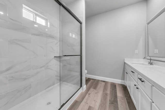 bathroom featuring toilet, a shower with shower door, hardwood / wood-style floors, and vanity