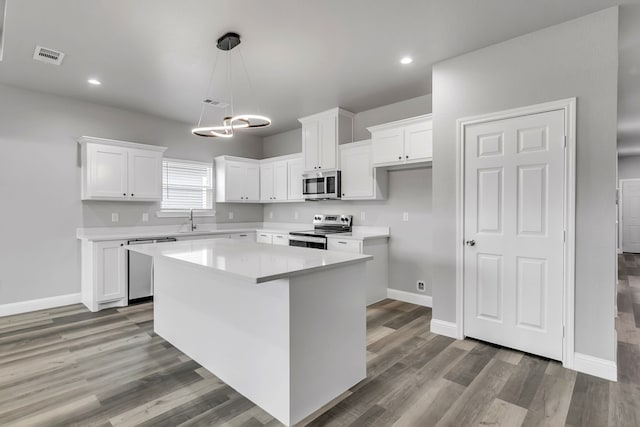 kitchen featuring stainless steel appliances, white cabinets, a kitchen island, and sink