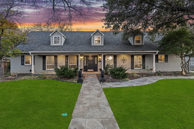 cape cod-style house with a yard and a porch