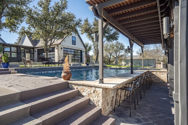 view of swimming pool featuring a bar and a patio