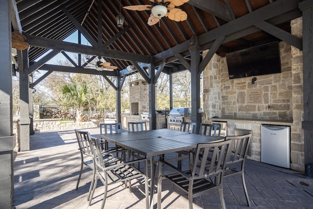 view of patio / terrace with an outdoor stone fireplace, a gazebo, a grill, ceiling fan, and area for grilling