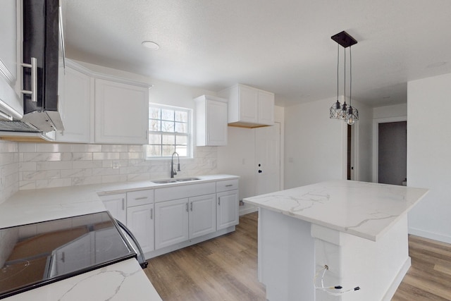 kitchen featuring backsplash, a center island, sink, light hardwood / wood-style flooring, and white cabinets