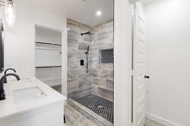 bathroom with a tile shower and vanity