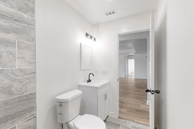 bathroom featuring wood-type flooring, toilet, and vanity