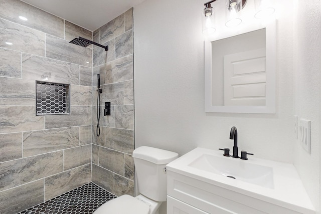 bathroom featuring toilet, vanity, and a tile shower