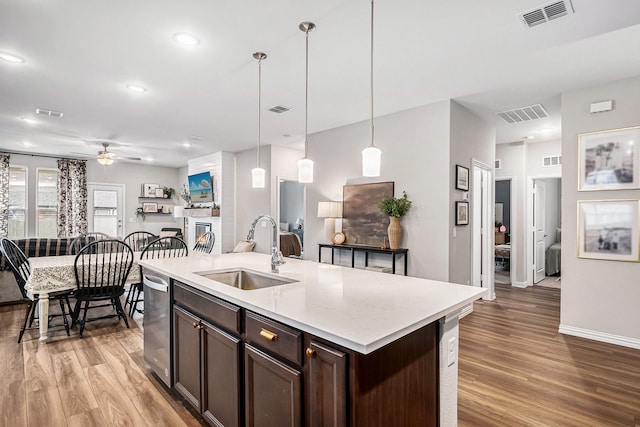 kitchen with ceiling fan, a kitchen island with sink, pendant lighting, dark brown cabinetry, and sink