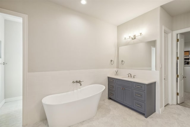 bathroom with vanity, a tub, tile walls, and tile patterned floors