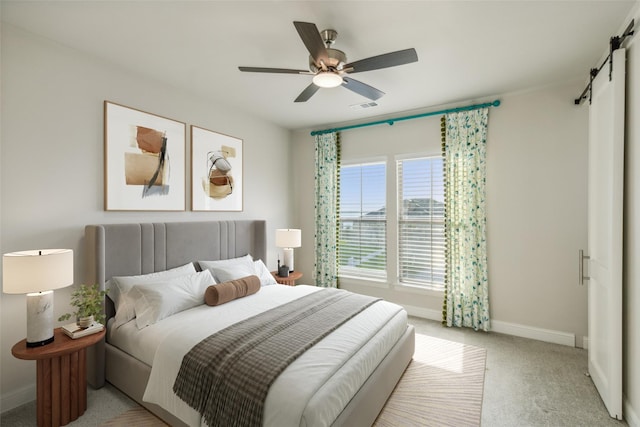 carpeted bedroom with ceiling fan and a barn door