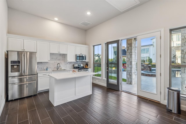 kitchen featuring a center island, sink, plenty of natural light, stainless steel appliances, and white cabinets