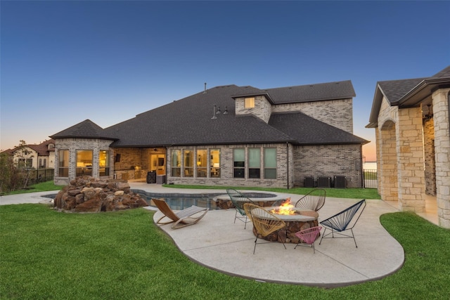 back house at dusk featuring a patio area, an outdoor fire pit, and a yard