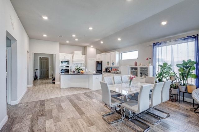 dining room featuring lofted ceiling and light wood-type flooring