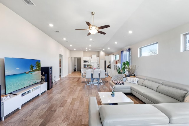 living room featuring ceiling fan, light hardwood / wood-style floors, and vaulted ceiling