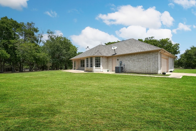 back of property featuring central AC unit, a yard, and a garage