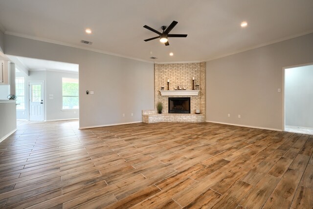 living room featuring ceiling fan, wood-type flooring, crown molding, and a fireplace